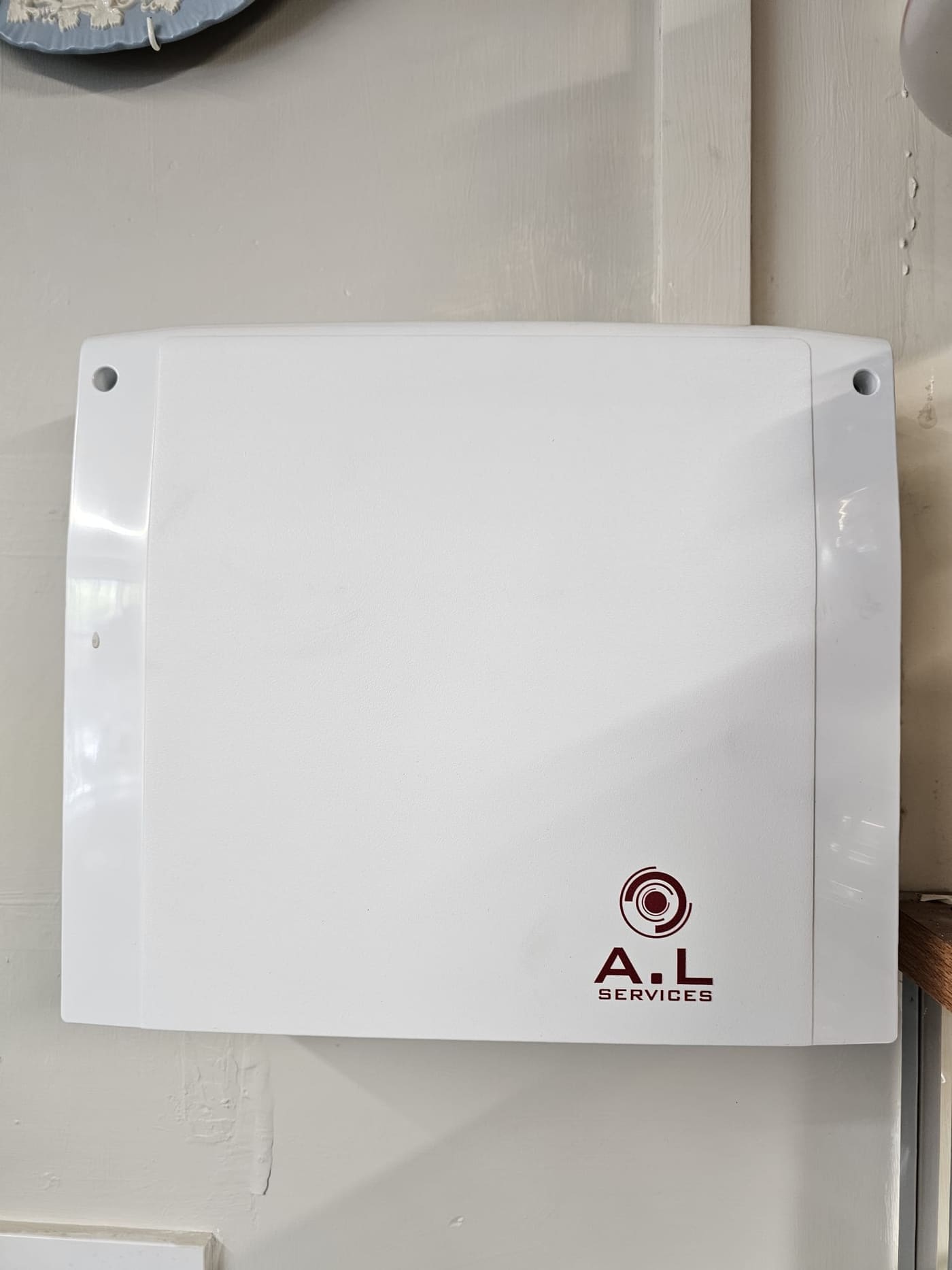 Close-up of a white intruder alarm panel carrying the ALServices logo