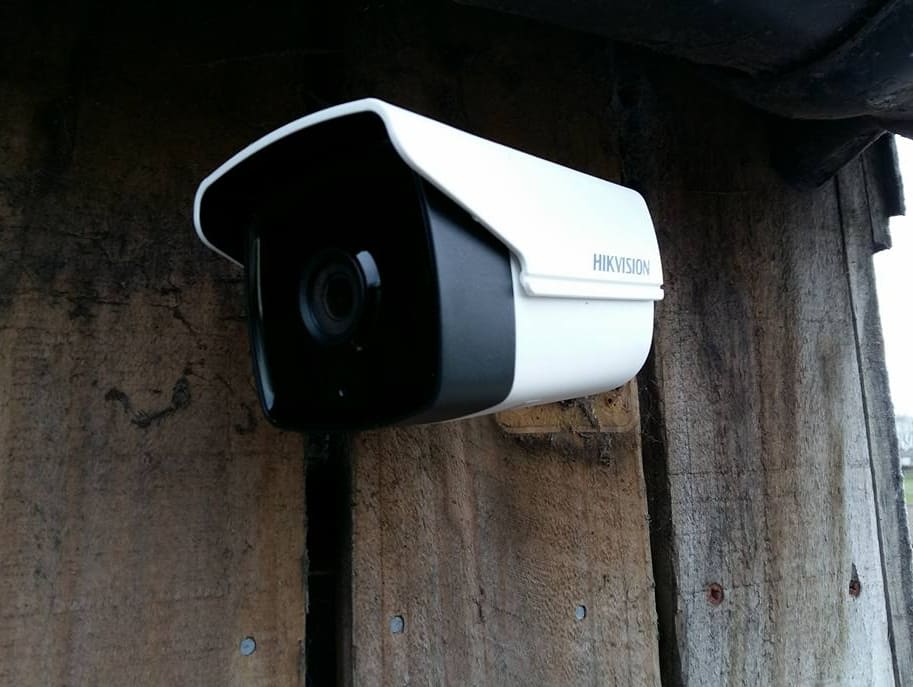 Hikvision bullet camera mounted on weathered timber cladding at a farm